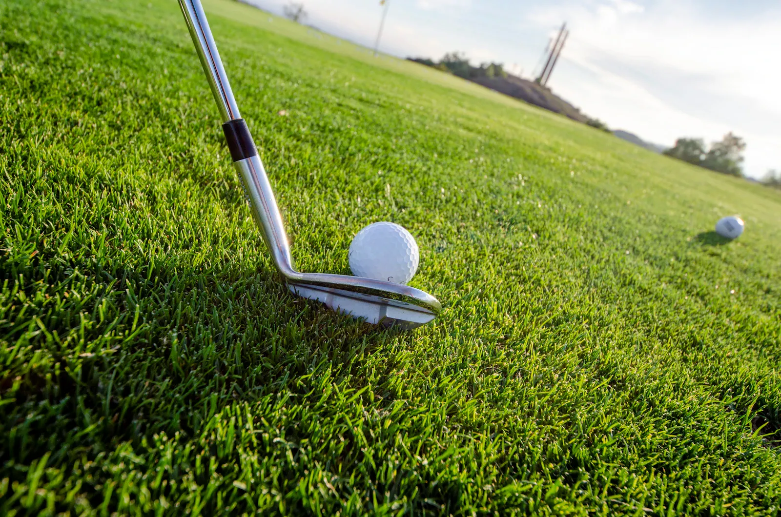 Tête de bâton posée derrière une balle de golf sur l’allée
